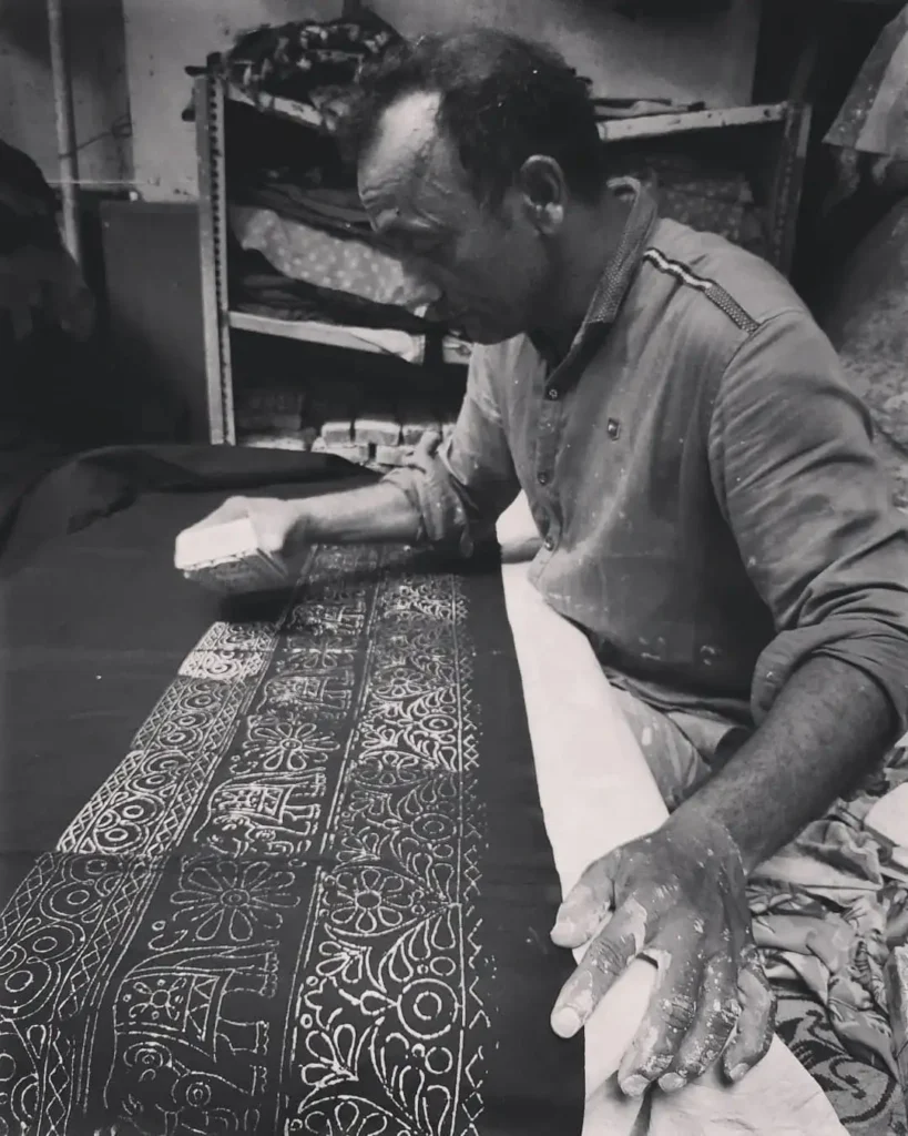 a men doing block printing on saree